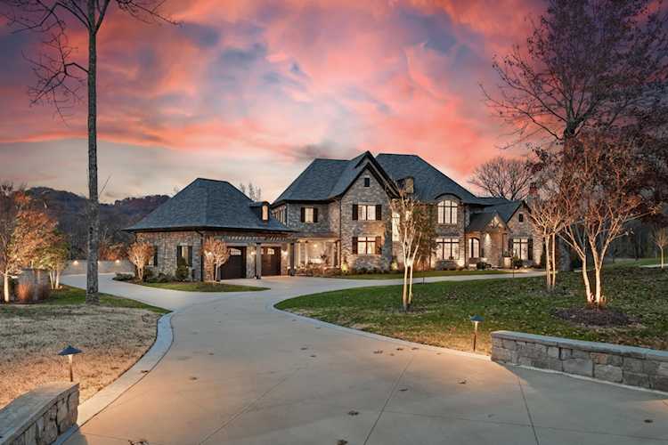 Front yard full of colorful wildflowers, statement boulders, a dry creek bed full of stone -- all in front of a light tan home